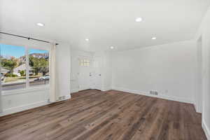 Unfurnished living room featuring recessed lighting and dark wood finished floors