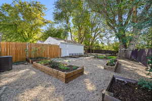 Fenced backyard featuring a vegetable garden and an outdoor structure