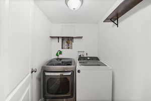 Downstairs laundry room featuring washing machine and clothes dryer