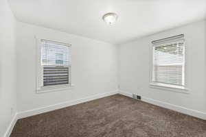 Empty room featuring dark colored carpet