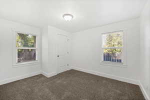 Spare room featuring dark carpet and baseboards