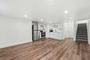 Second kitchen with white cabinets, recessed lighting, stainless steel appliances, light countertops, and dark wood-style flooring
