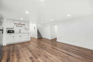 Kitchen featuring white cabinetry, light countertops, dark wood-style floors, recessed lighting, and black microwave