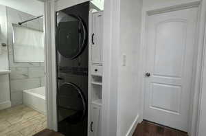 Upstairs laundry area with stacked washer / drying machine and dark wood finished floors