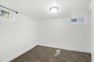 Below grade area with plenty of natural light, a textured ceiling, and carpet flooring