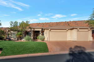 Prairie-style home featuring an attached garage, a front yard, driveway, stucco siding, and a tiled roof