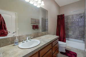 Full bathroom with shower / bath combo with shower curtain, vanity, and light tile patterned flooring