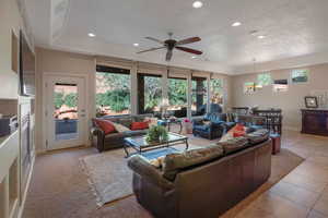 Living room featuring healthy amount of natural light, recessed lighting, a ceiling fan, light tile patterned floors, and a chandelier