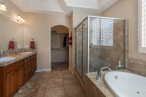 Full bathroom with a walk in closet, a garden tub, double vanity, a shower stall, and plenty of natural light