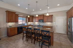 Kitchen featuring brown cabinets, backsplash, dark stone counters, and recessed lighting