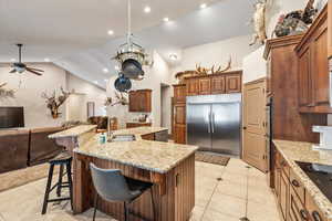 Kitchen with open floor plan, stainless steel appliances, a breakfast bar area, a spacious island, and brown cabinets
