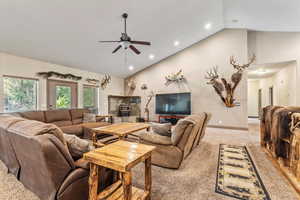 Living area with carpet, high vaulted ceiling, recessed lighting, and a ceiling fan