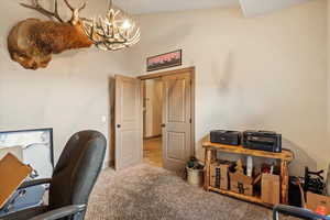 Office area featuring carpet, a chandelier, and vaulted ceiling