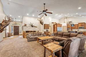 Living room with high vaulted ceiling, light carpet, ceiling fan, and recessed lighting