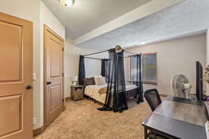 Bedroom featuring a textured ceiling and light colored carpet
