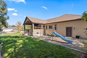Rear view of property with a yard, roof with shingles, stucco siding, and a patio