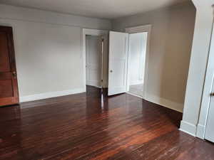 Unfurnished bedroom featuring baseboards and dark wood-type flooring