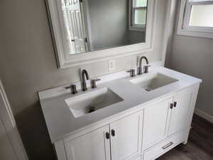 Bathroom with double vanity and dark wood-style floors