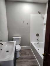 Bathroom with dark wood-style flooring, shower / washtub combination, and vanity