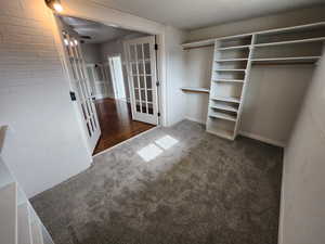 Spacious closet featuring french doors and dark colored carpet