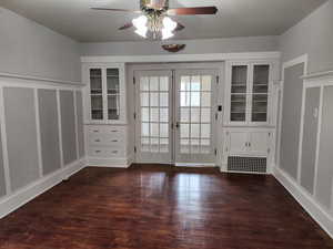 Doorway to outside with wood finished floors, ceiling fan, french doors, and a decorative wall