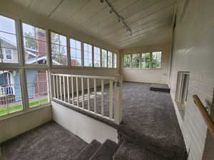 Unfurnished sunroom featuring carpet floors, lofted ceiling, and track lighting