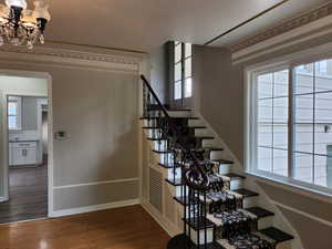 Stairway with wood finished floors and a chandelier