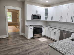 Kitchen with white cabinetry, light stone counters, appliances with stainless steel finishes, light wood-style flooring, and recessed lighting