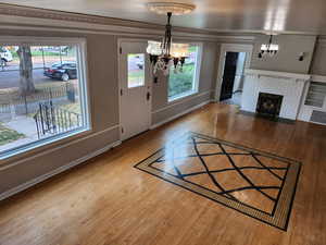 Foyer entrance featuring hardwood / wood-style flooring, a chandelier, a fireplace, and crown molding