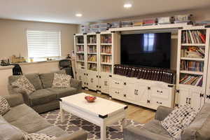 Living area with light wood-type flooring and recessed lighting