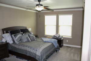 Bedroom with crown molding, carpet, and a ceiling fan