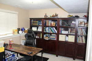 Home office with a textured ceiling and light colored carpet