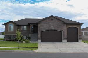 View of front facade featuring a garage, concrete driveway, brick siding, a front yard, and stucco siding