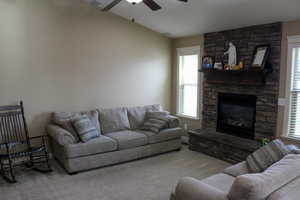 Carpeted living room featuring a fireplace and a ceiling fan