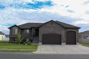 View of front of home with an attached garage, concrete driveway, brick siding, and stucco siding
