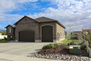 View of front of property featuring a garage, driveway, and brick siding