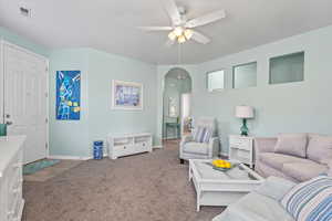 Living room featuring arched walkways, carpet, and ceiling fan