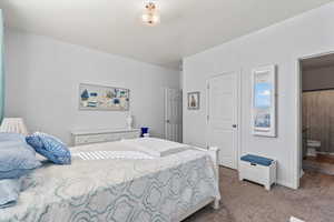 Carpeted bedroom with ensuite bath and baseboards
