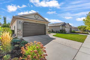 Ranch-style house with stone siding, driveway, and a front yard