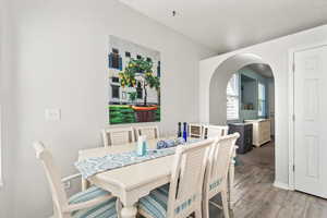 Dining space featuring arched walkways and light wood-style flooring