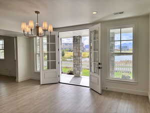 Doorway with wood finished floors, a chandelier, recessed lighting, and a water view
