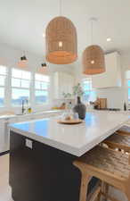 Kitchen featuring white cabinets, pendant lighting, dark cabinets, a center island, and a breakfast bar area
