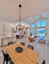 Dining area featuring light wood-style floors, high vaulted ceiling, a chandelier, beamed ceiling, and recessed lighting