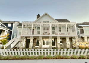 View of front of house featuring stone siding, a chimney, a fenced front yard, and stairway