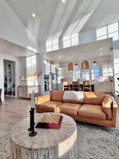 Living room featuring recessed lighting, high vaulted ceiling, and light wood-style floors