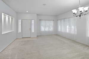 Foyer featuring plenty of natural light, light carpet, and a chandelier