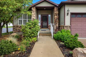 Doorway to property with stone siding and an attached garage