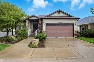 View of front facade with driveway, an attached garage, and stone siding