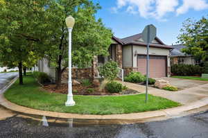 View of front of property with stone siding, concrete driveway, an attached garage, and a front yard