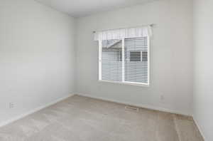 Spare room featuring light colored carpet and baseboards